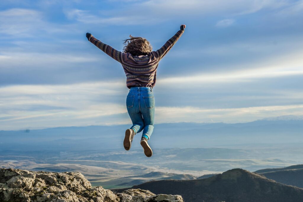 Person jumping on a mountain peak, celebrating adventure and freedom.
